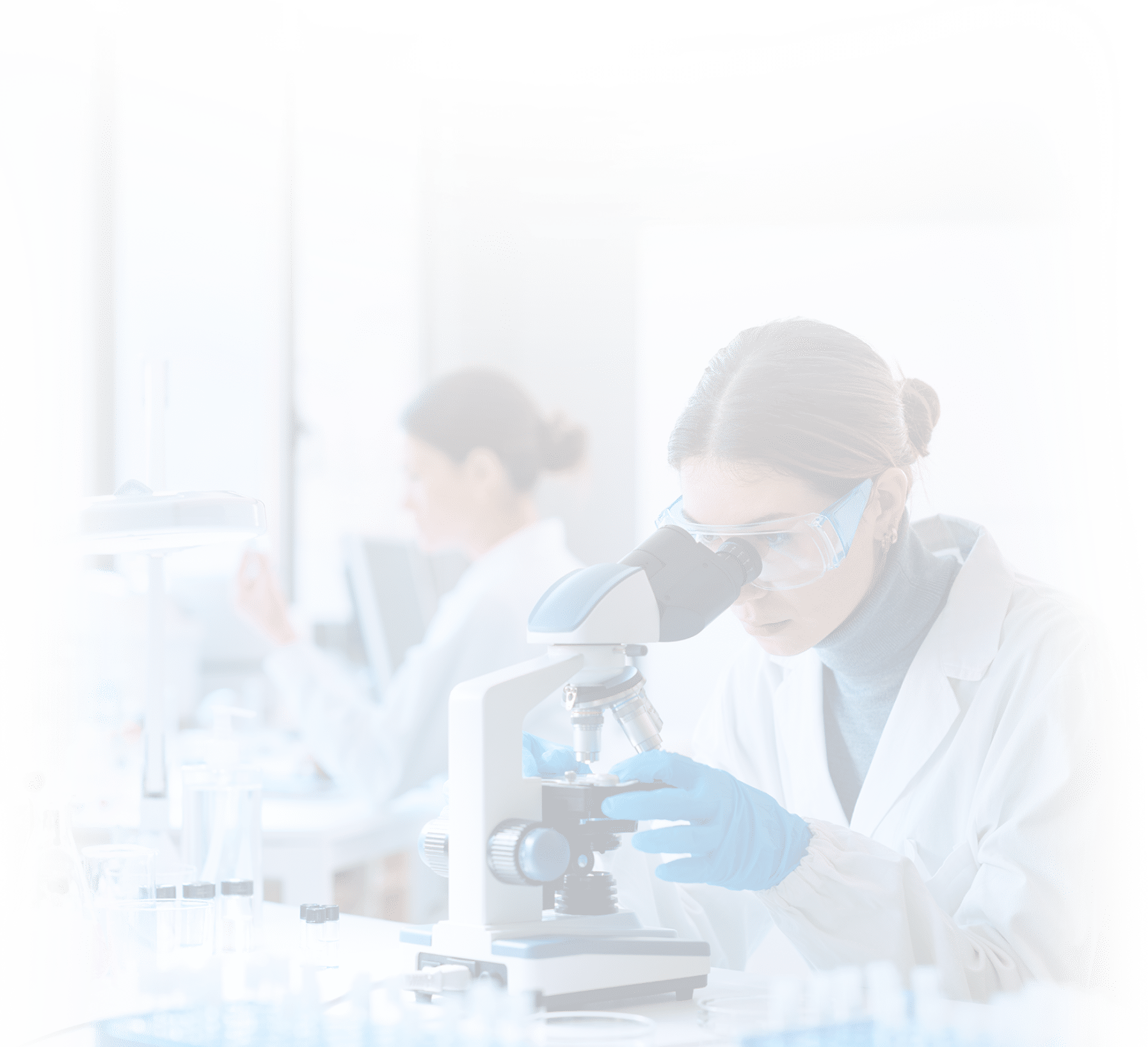 Young scientists conducting research investigations in a medical laboratory, a researcher in the foreground is using a microscope