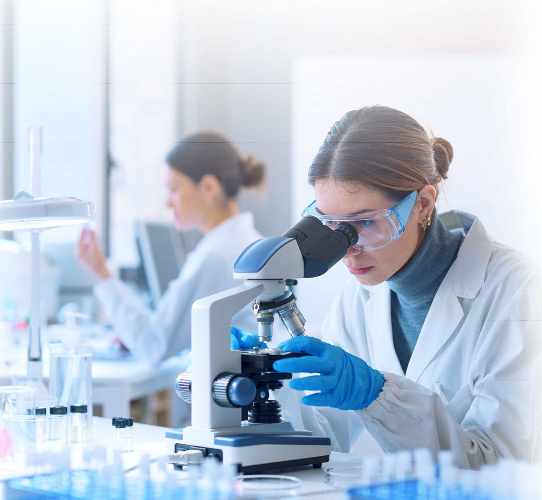 Young scientists conducting research investigations in a medical laboratory, a researcher in the foreground is using a microscope